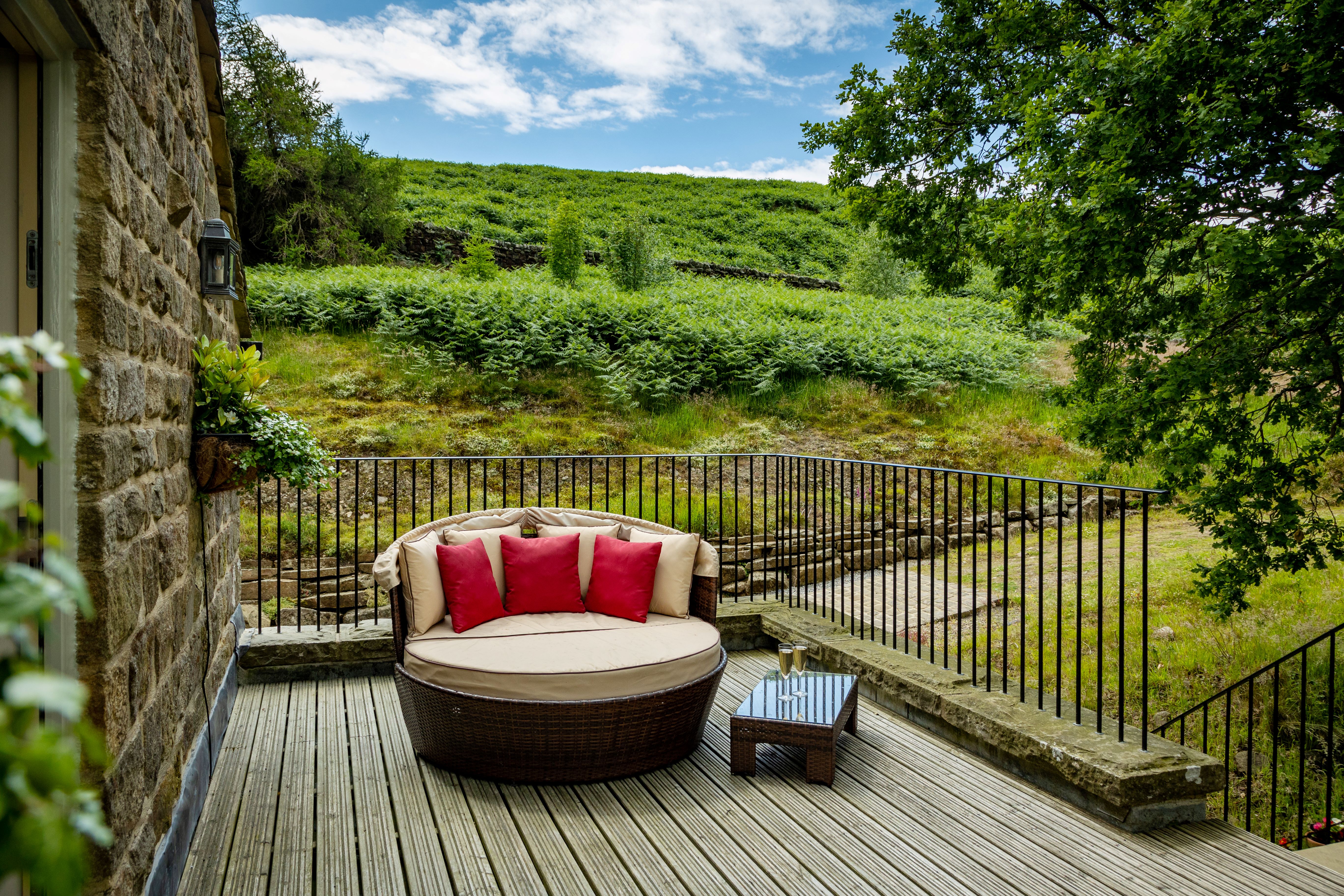 Outdoor sofa on a raised terrace with a view of a lush green hillside in the background