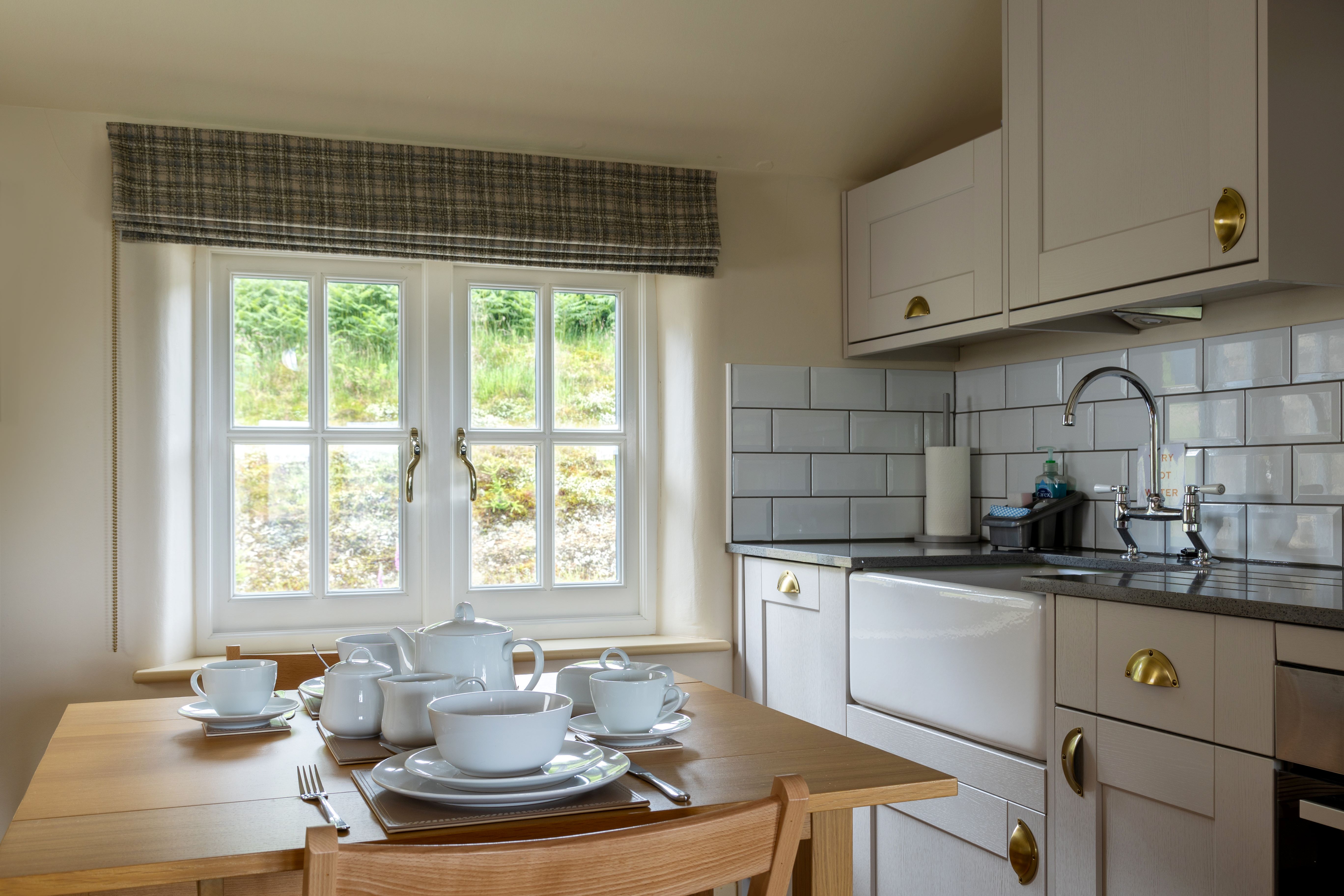 A wooden table with place settings for two next to a window