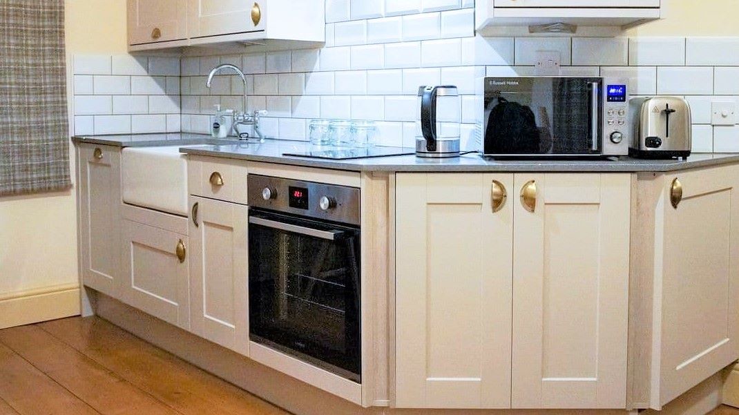 Kitchen workspace with induction hob, oven, microwave, kettle, toaster, and sink