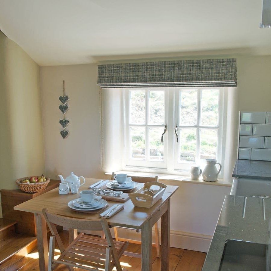 A wooden table with place settings for two next to a window